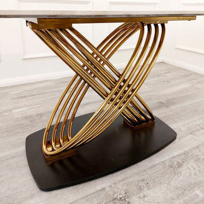 Modern dining table with gold metal base and marble top on a wooden floor.